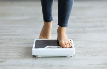 Woman stepping on scales to check weight.
